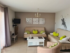 Ein Wohnzimmer mit Sofa, Couchtisch, Fernseher und Kunstwerken an der Wand.