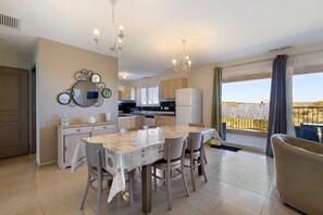 A modern kitchen with a dining area, a large mirror, and a view through a balcony.