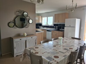 Eine moderne Küche mit Holzausstattung, einem weißen Kühlschrank und einem Esstisch mit gemustertem Tischläufer.