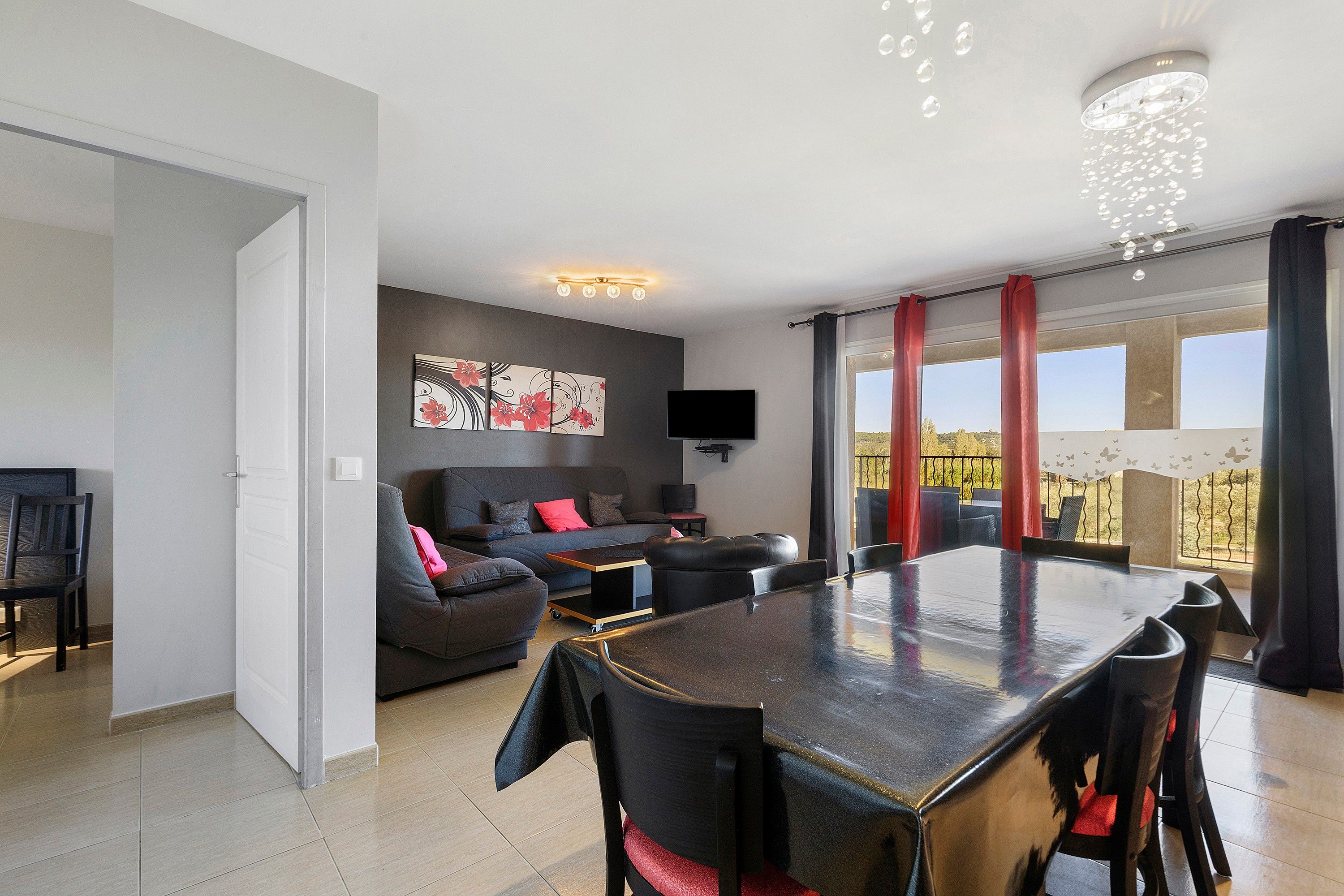 A modern living space with a dining area, a sofa set, and a flat-screen TV.