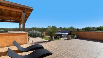 A rooftop terrace with a wooden pergola, a hot tub, and a barbecue area.