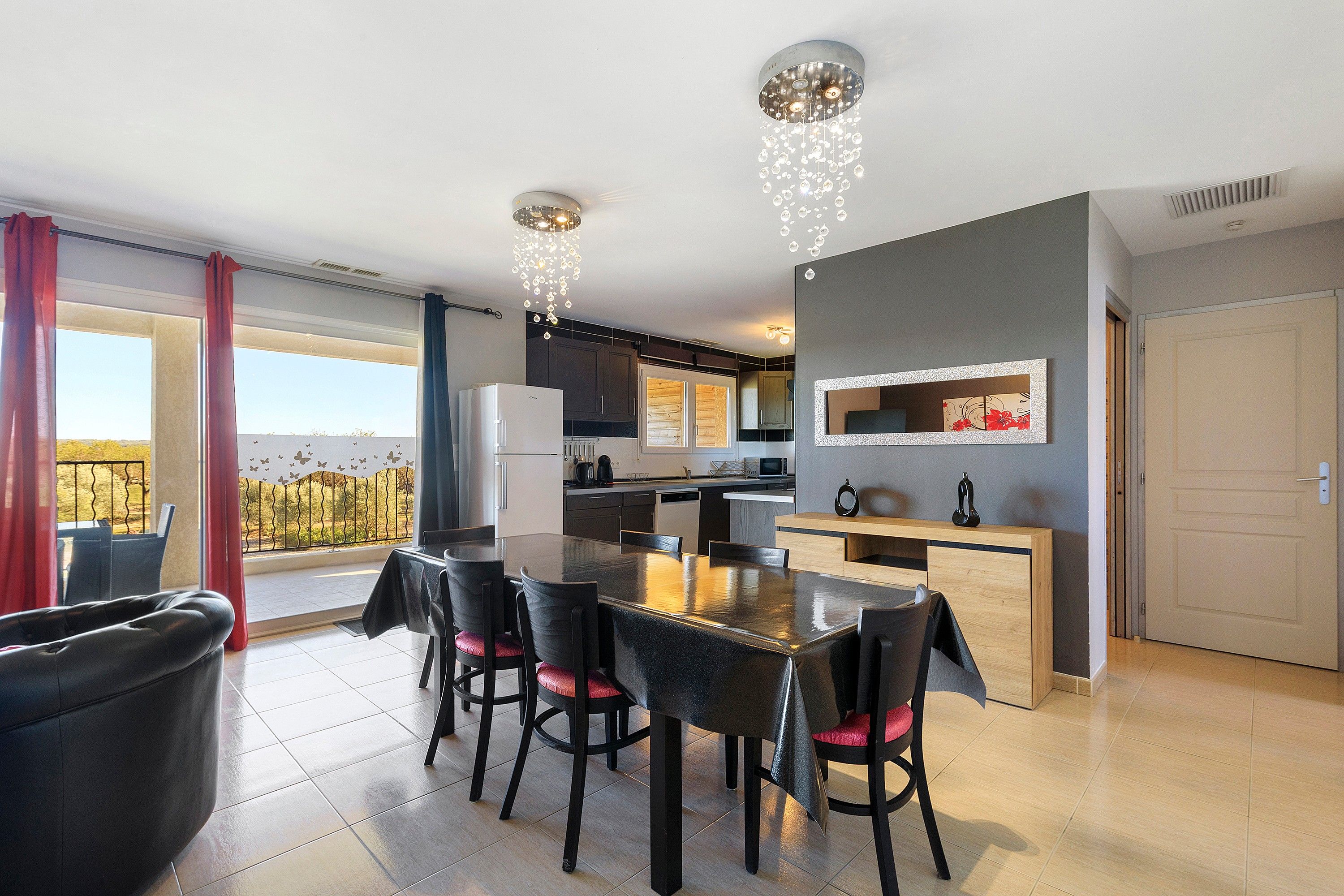 Une cuisine moderne avec un coin repas, un balcon offrant une vue agréable et un luminaire décoratif au plafond.