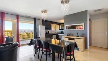 Une cuisine moderne avec un coin repas, un balcon offrant une vue agréable et un luminaire décoratif au plafond.