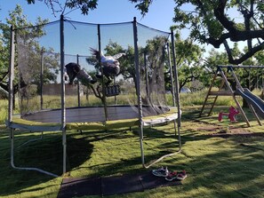 A trampoline with a safety net, surrounded by grass and trees. - Apartment 'La Valencianne' with Wi-Fi and Air Conditioning (Paulhan)