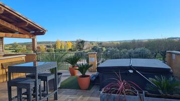 Eine Dachterrasse mit Gartenmöbeln, Topfpflanzen und Blick auf die Landschaft.