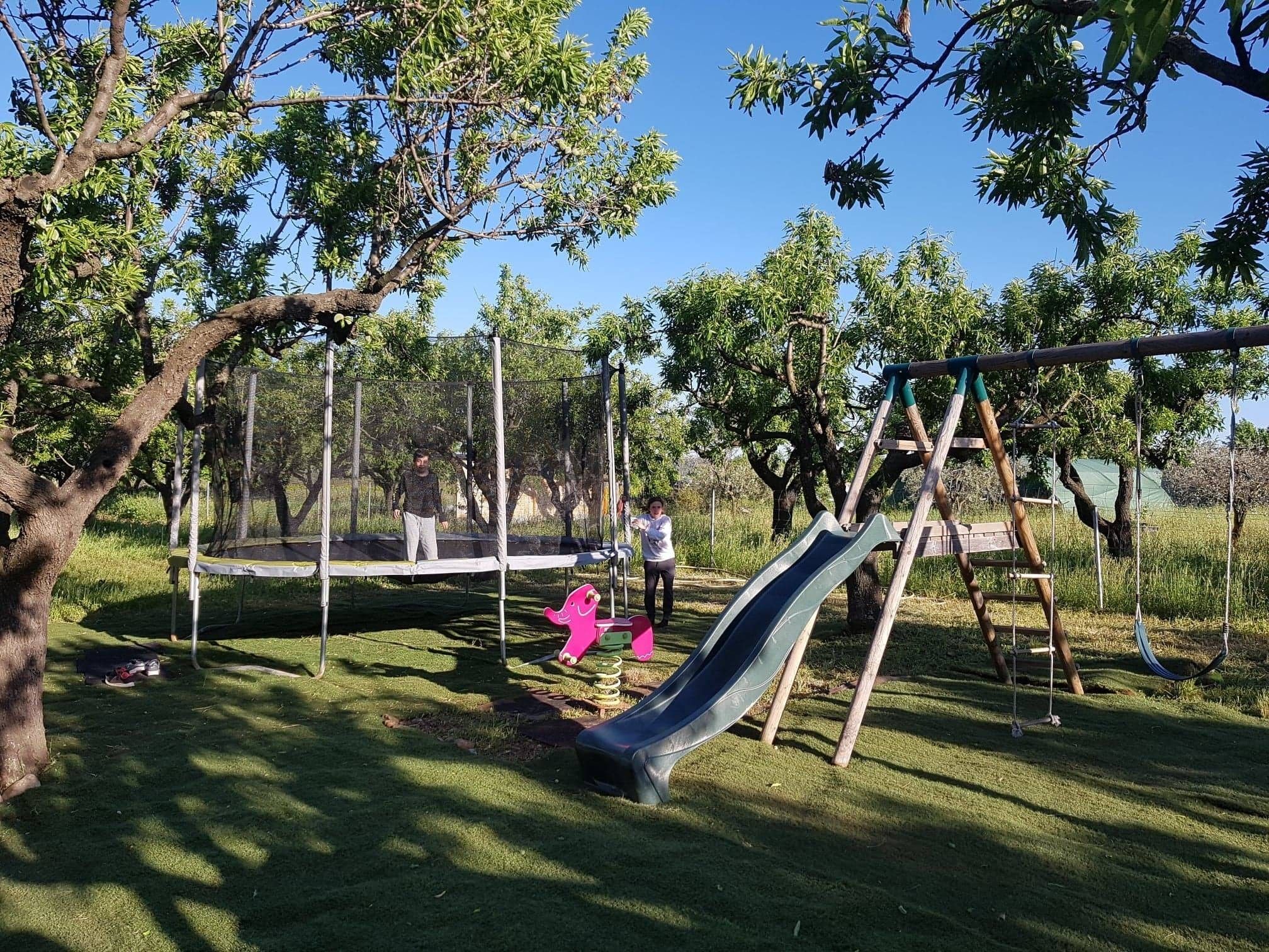 Ein Spielplatz mit Rutsche, Schaukeln und Trampolin.