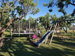 A playground with a slide, swings, and a trampoline. - Apartment 'La Valencianne' with Wi-Fi and Air Conditioning (Paulhan)