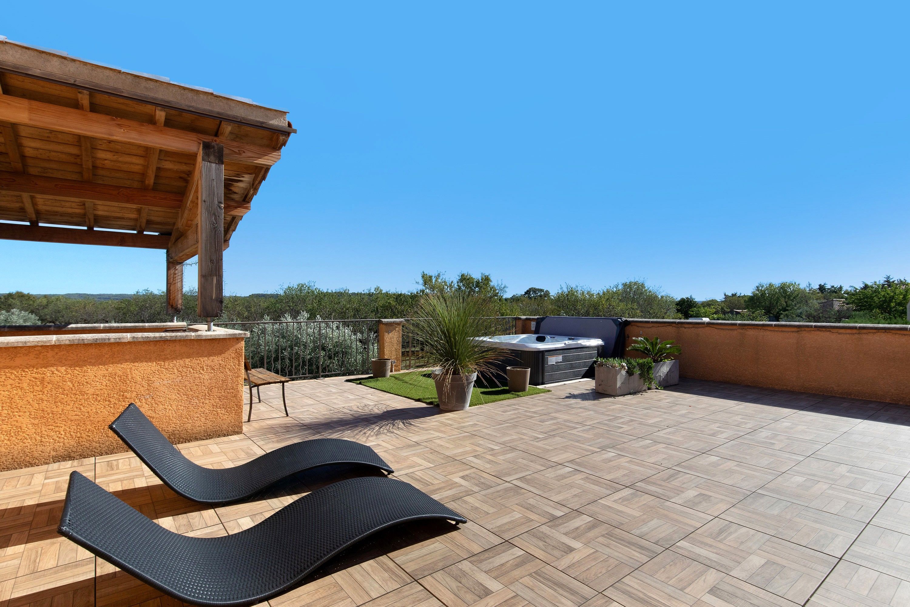 Eine Dachterrasse mit einer Holzpergola, einem Whirlpool und einer Grillgegend.