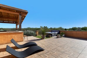 A rooftop terrace with a wooden pergola, a hot tub, and a barbecue area.