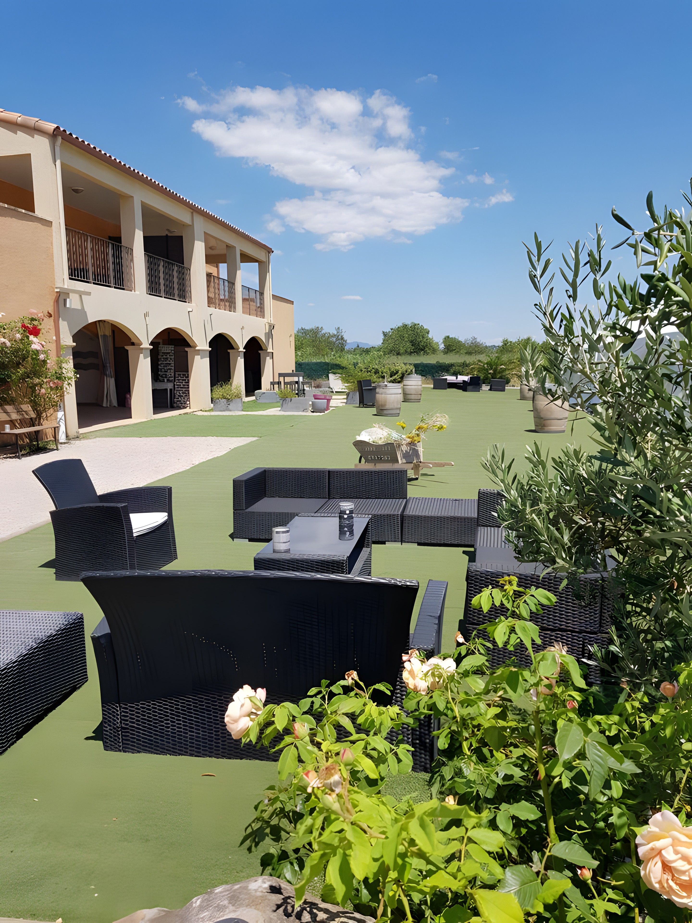A courtyard with outdoor seating, a building with arches, and greenery.