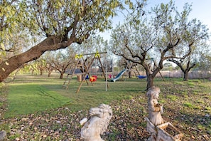 A playground with swings, slides, and climbing structures surrounded by trees and a grassy area. - Apartment 'La Baccara' with Wi-Fi and Air Conditioning (Paulhan)