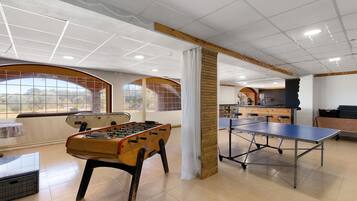 Une pièce équipée d’un baby-foot, d’une table de ping-pong et d’un bar avec des tabourets.