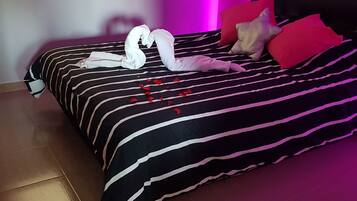Un letto con biancheria a righe, cuscini e un'elegante decorazione di asciugamani a forma di cigno.