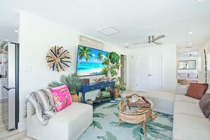 Ein Wohnzimmer mit einer Couch, einem Couchtisch, einem Fernseher und einem Deckenventilator.