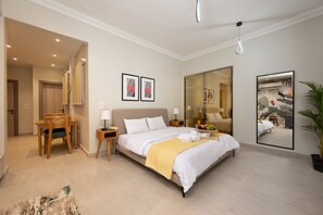 A hotel room with a large bed, bedside tables, a desk with a chair, a mirror, and artwork on the walls. - Luxury stay at Degla by Spacey #68 (Cairo)