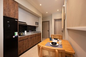 A compact kitchen with a refrigerator, stove, and wooden cabinets. There is a dining table with chairs and a small window. - Luxury stay at Degla by Spacey #68 (Cairo)