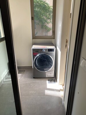 A compact laundry room with a washing machine, a window, and a tiled floor.
