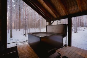 A hot tub in a wooden cabin with a snowy forest view. - Tieva Chalets Levi by Aavalevi (Levi)