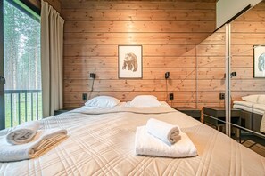 A wooden-paneled room with a bed, two bedside tables, and a window with curtains. - Tieva Chalets Levi by Aavalevi (Levi)