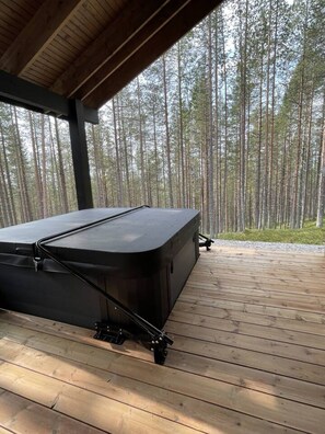 A hot tub under a wooden deck with a forest view. - Tieva Chalets Levi by Aavalevi (Levi)