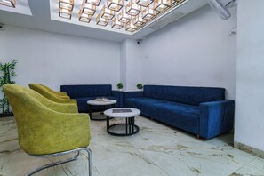 Uma área de estar moderna com um sofá azul, cadeiras amarelas e duas mesinhas.