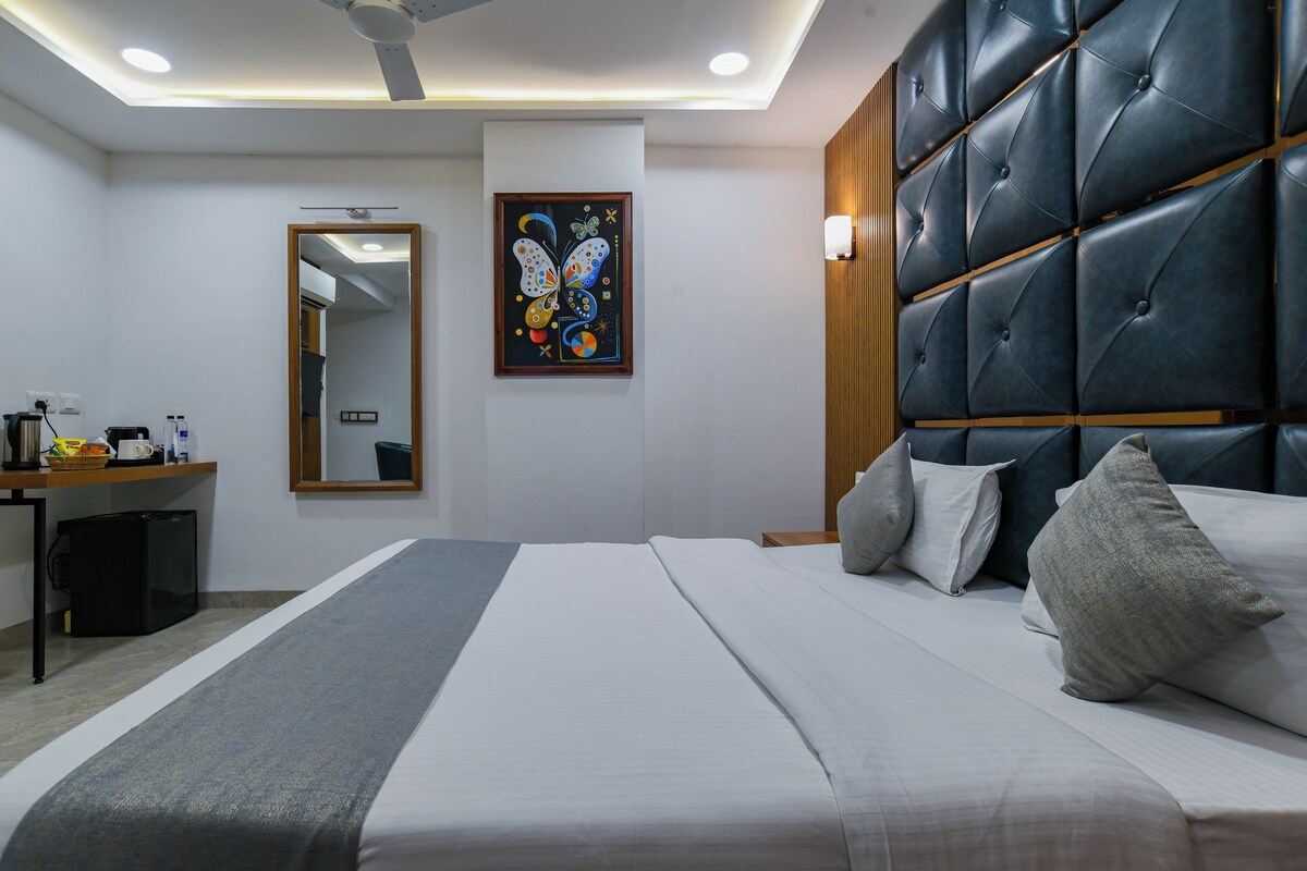 Una habitación de hotel con cama, mesita de noche, espejo, un cuadro y ventilador de techo.