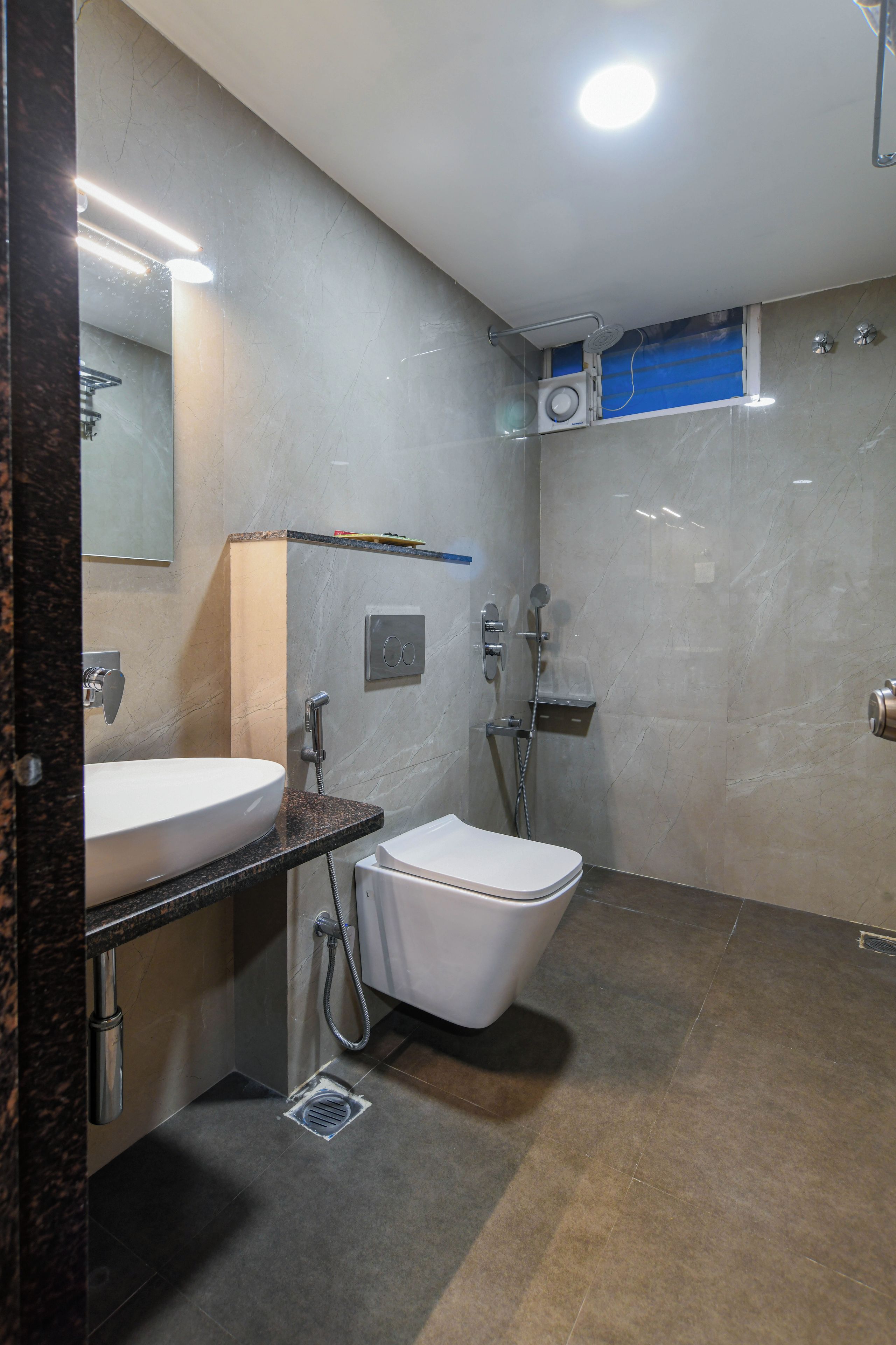 Un baño moderno con un lavamanos blanco, un inodoro y una zona de ducha.