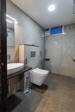 Un baño moderno con un lavamanos blanco, un inodoro y una zona de ducha.