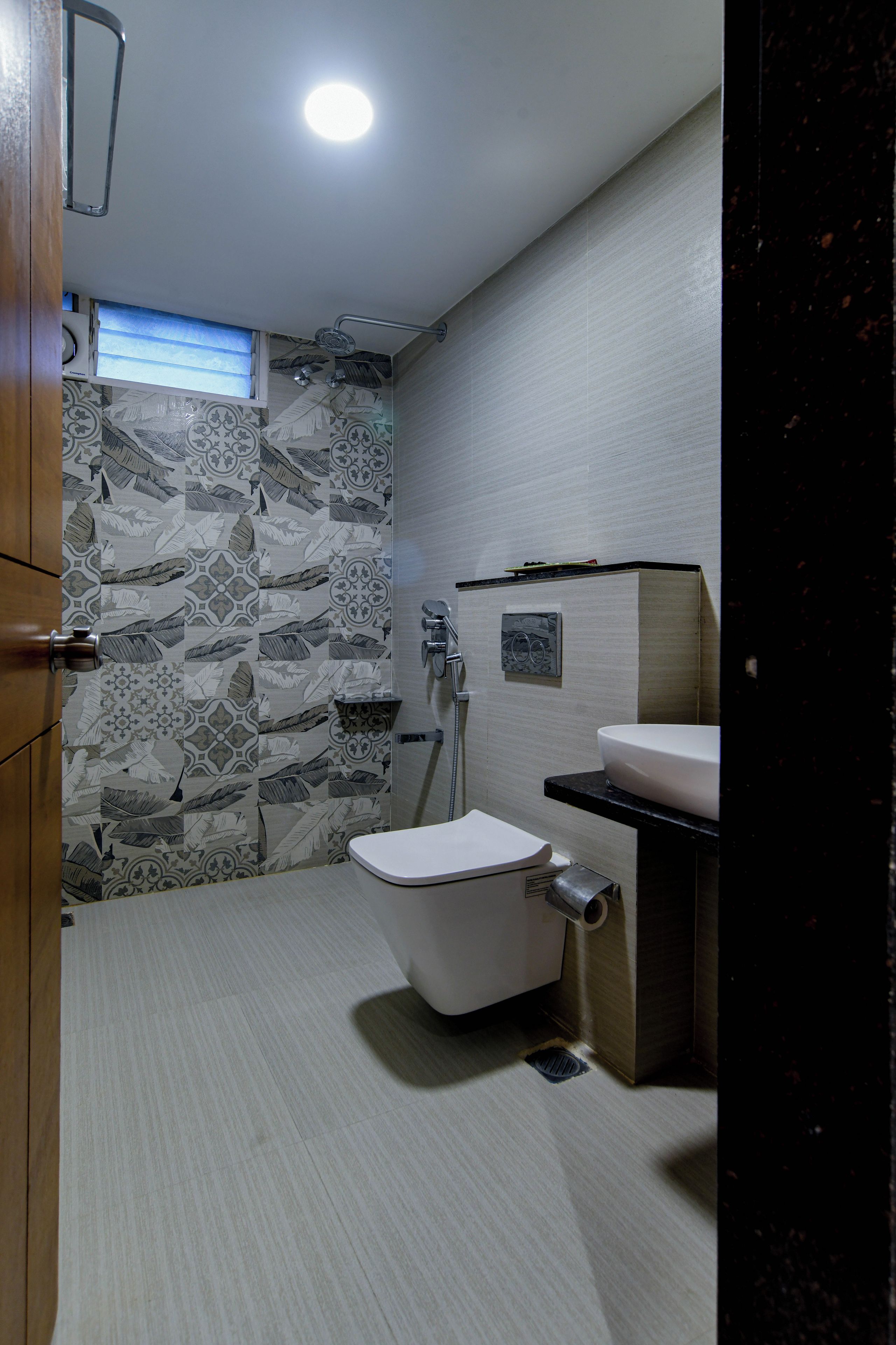 Un baño con inodoro, lavabo, ducha y azulejos decorativos.