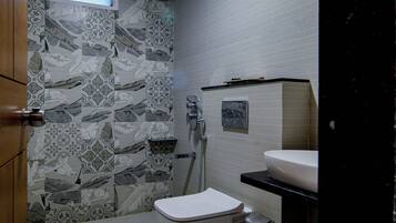 Un baño con inodoro, lavabo, ducha y azulejos decorativos.