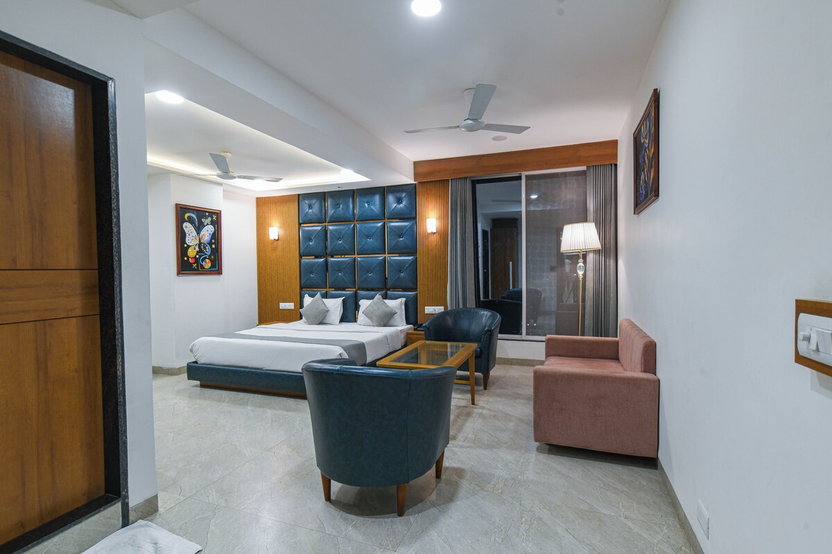 Una habitación de hotel moderna con cama, zona de estar y un gran ventanal.