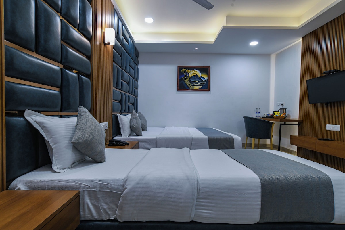 A hotel room with two beds, a desk, a television, and a painting on the wall.