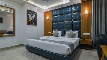 A modern hotel room with a large bed, a ceiling fan, a wall-mounted light, and a bedside table with a phone.