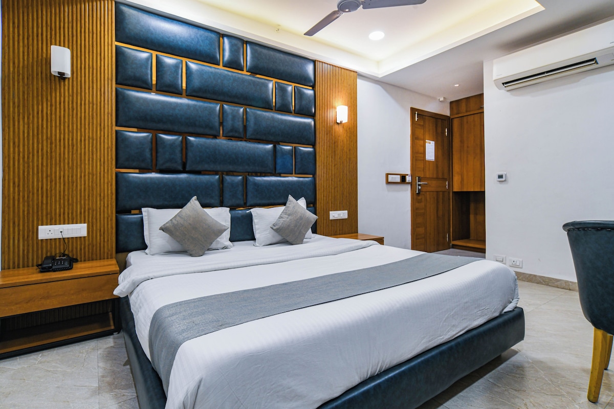 A modern bedroom with a large bed, wooden paneling on the walls, a ceiling fan, and an air conditioning unit.