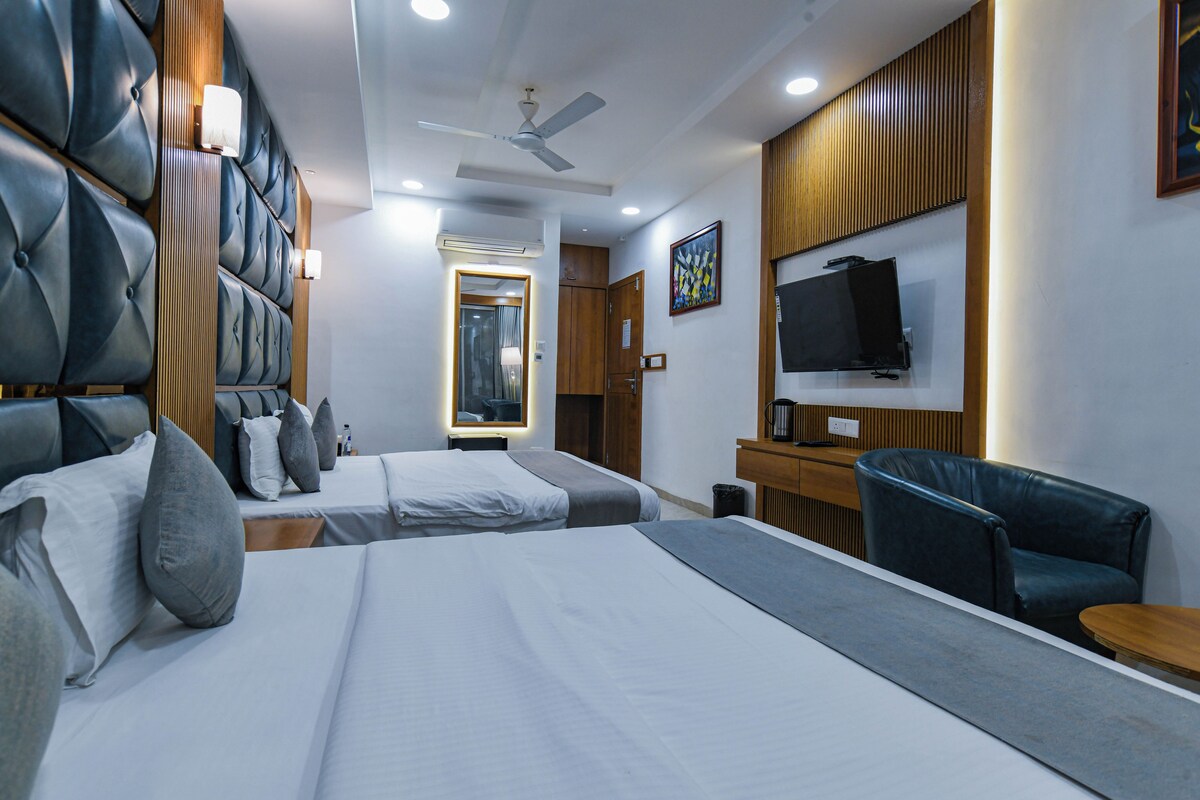 Habitación de hotel con dos camas, un escritorio, una silla, un televisor y un ventilador de techo.