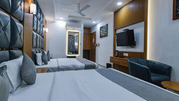 Habitación de hotel con dos camas, un escritorio, una silla, un televisor y un ventilador de techo.
