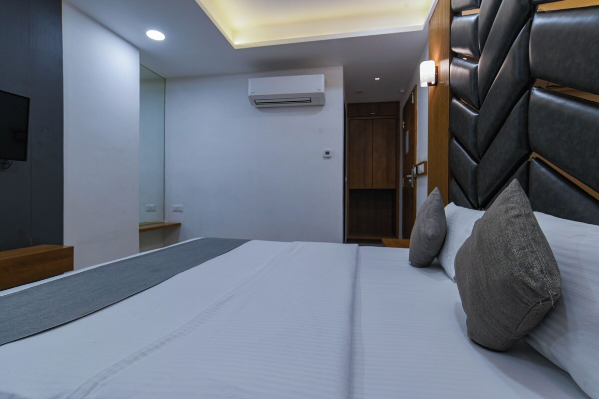 A modern hotel room with a large bed, a flat-screen TV, and a ceiling light fixture.