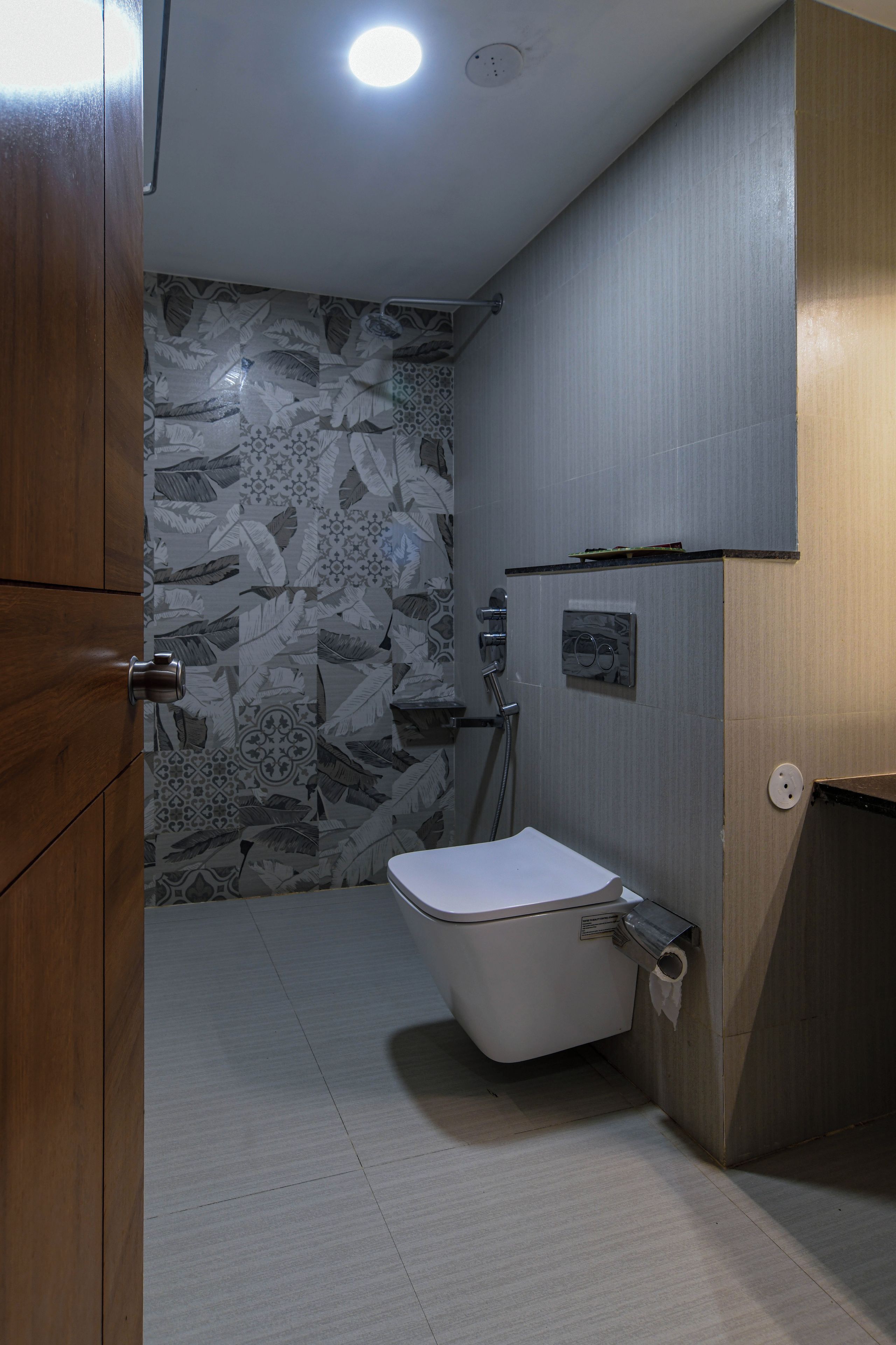 Un baño con inodoro, ducha y baldosas de pared con diseño.