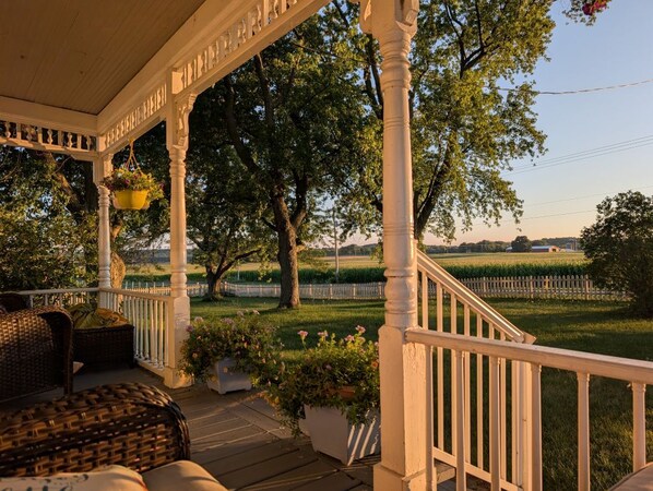 A covered porch with wicker furniture and hanging flower baskets.