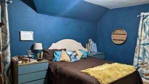 A bedroom with a bed, a nightstand, a lamp, and a wall-mounted round mirror. - 4-bedroom updated Farmhouse just 40 minutes north of Milwaukee (Cedar Grove)