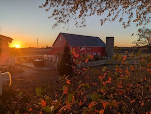 A red barn with a flag, surrounded by a fence and trees.