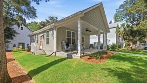 A single-story house with a covered porch, a front door, and a small front yard with grass and mulch. - Our Little Cottage by the Sea - NEW RENTAL (Pawleys Island)