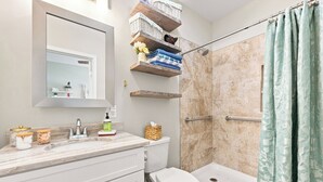 A bathroom with a shower, toilet, and vanity with storage. - Our Little Cottage by the Sea - NEW RENTAL (Pawleys Island)