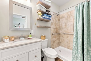 Ein Badezimmer mit Dusche, Toilette und Waschtisch mit Stauraum.