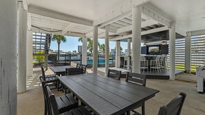 Ein Außenbereich mit Terrassengarnitur, Pool und Bar.