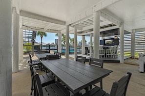 An outdoor patio area with tables and chairs, a pool, and a bar area. - Boat-Friendly Waterfront Luxury Home in Gulf Shores | Sleeps 19 (Gulf Shores)