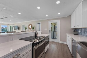A modern kitchen with a large island, built-in oven, and white cabinetry. - Boat-Friendly Waterfront Luxury Home in Gulf Shores | Sleeps 19 (Gulf Shores)