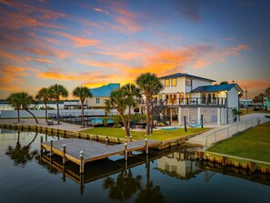 A waterfront property with a dock, a swimming pool, and a multi-story building with balconies. - Boat-Friendly Waterfront Luxury Home in Gulf Shores | Sleeps 19 (Gulf Shores)