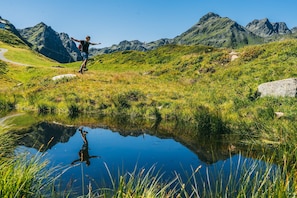 A person jumping in a natural setting with a mountain backdrop and a reflective water body. - Modern Suite With Garden or Loggia (Gaschurn)