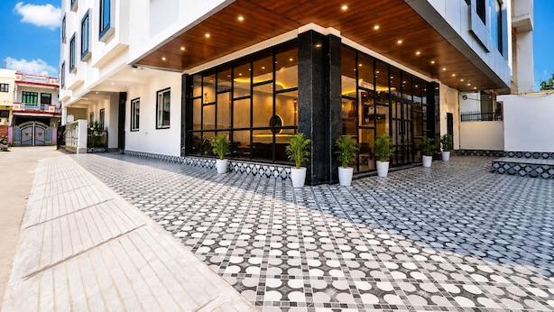 Ein moderner Hotel Eingang mit gefliestem Gehweg, großen Fenstern und Blumentöpfen.